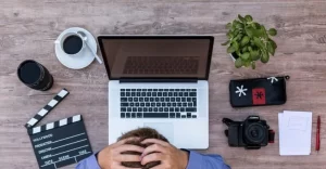 frustrated man in front of laptop with film objects around it